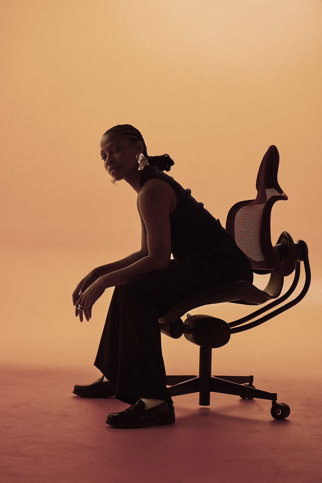 Person sitting on a modern office chair against an orange background