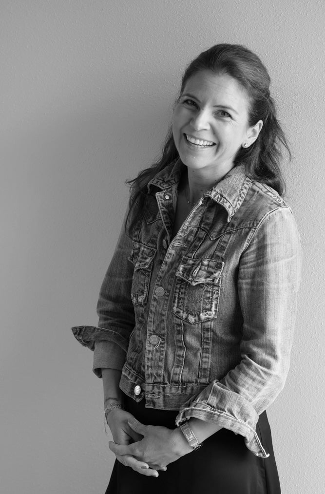 Black and white photo of a woman wearing a denim jacket against a plain background